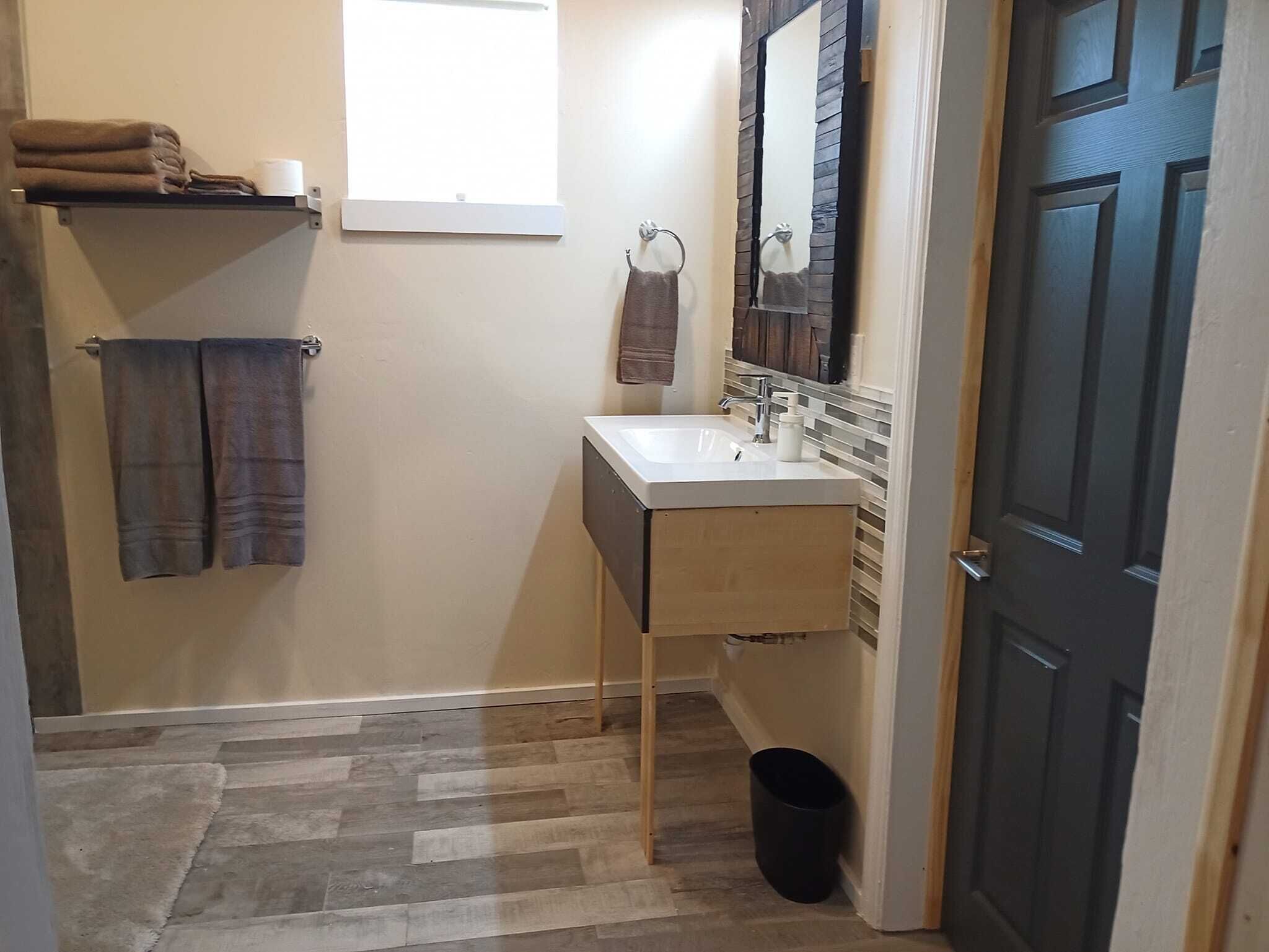 A bathroom with a wooden vanity, a sink, a mirror, and a towel rack.