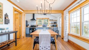 A modern kitchen with wooden cabinets, a central island, and a chandelier.