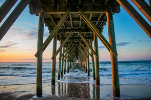A wooden pier extending into the ocean with a clear sky above. - Beautifully pristine bungalow not far from the beach and close to all the shops  (Surf City)