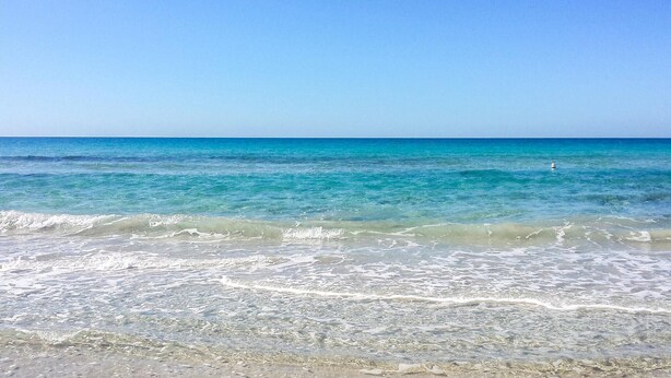 Une plage à l’eau turquoise et limpide, où les vagues sont douces.