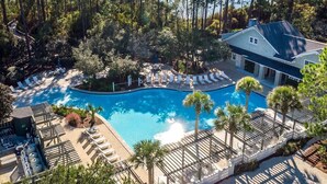 Ein Resort mit Schwimmbecken, umgeben von Liegestühlen und Palmen, mit einem Gebäude direkt am Pool.