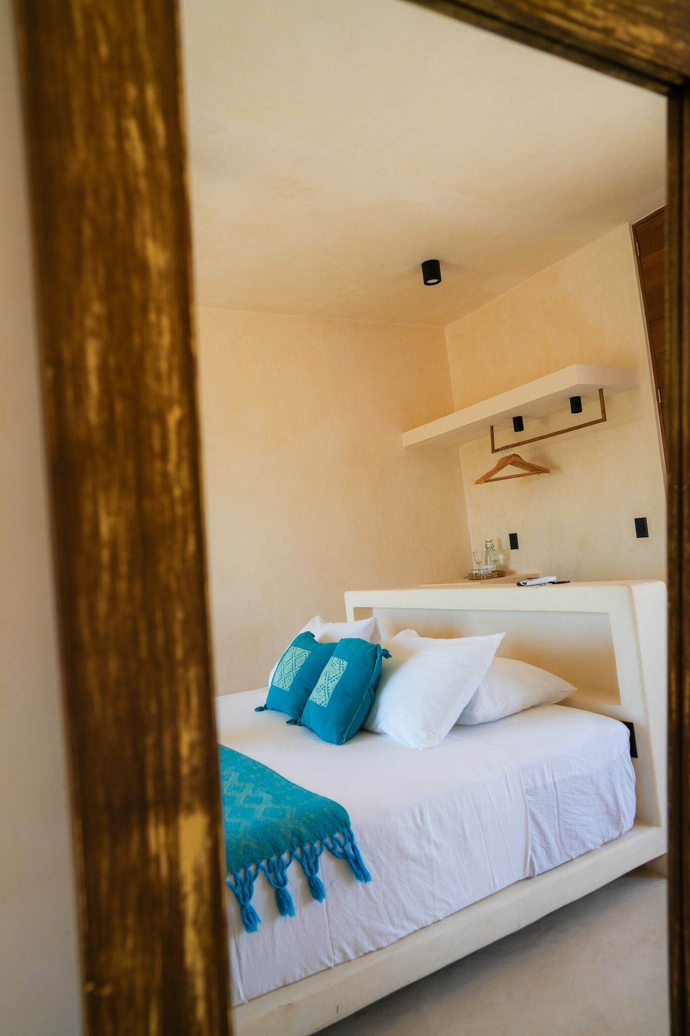 Un dormitorio con cama, almohadas, una mesita de noche y una lámpara colgante.