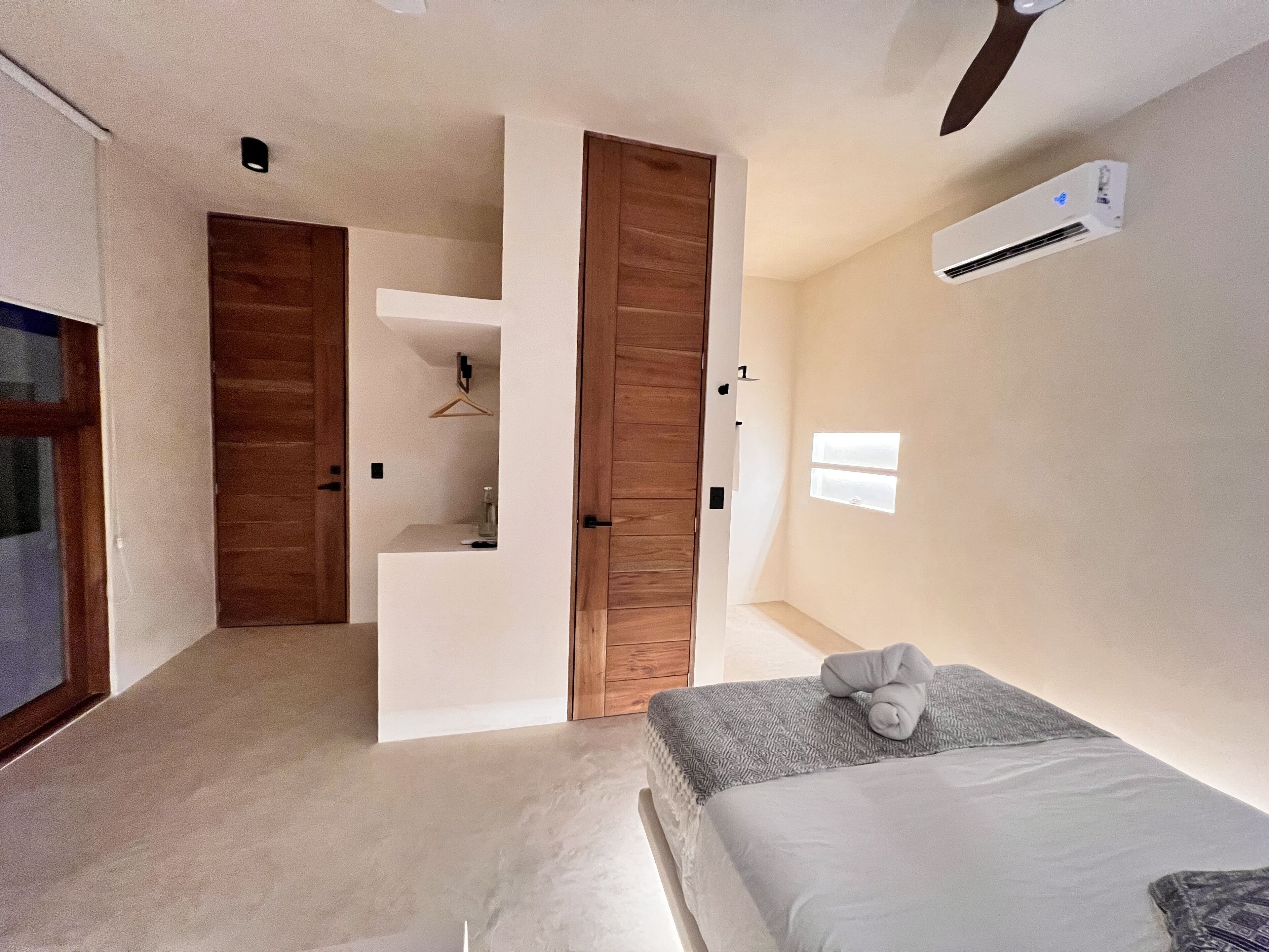 Un dormitorio con cama, toalla colgada, armario, escritorio pequeño y ventana.