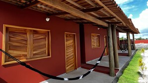 Un bâtiment à la façade rouge, doté de portes en bois et d’une pergola en bois.