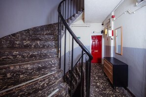 Stairs lead to a room with a red door and a wooden dresser.