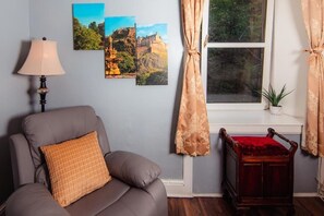 Relax in this inviting room with a sofa, side table, and floor lamp, offering a view of the lush green landscape.