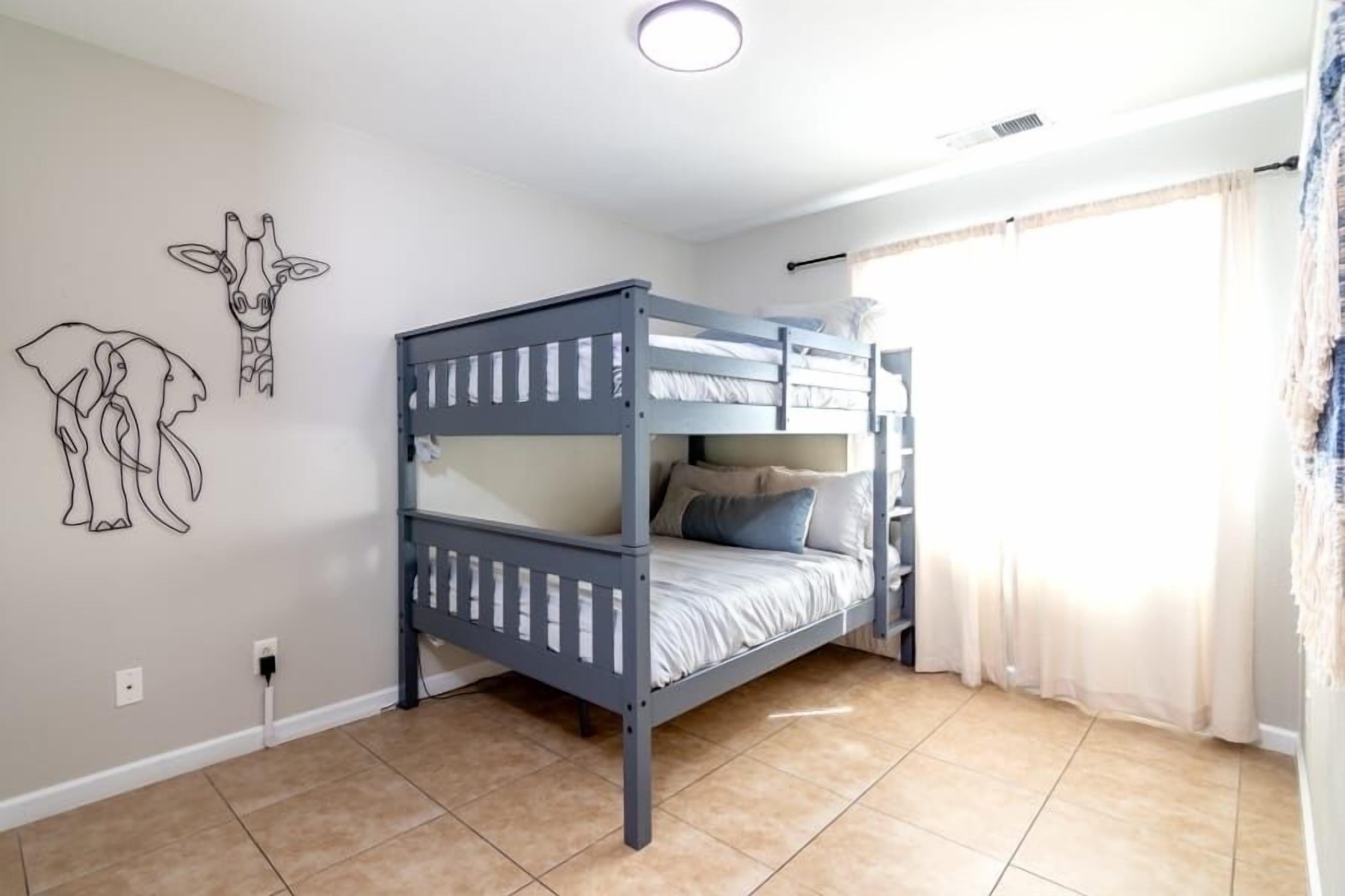 A bedroom with a bunk bed, a wall with animal line drawings, and a window with curtains.
