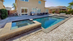 Ein wohnlicher Garten mit Swimmingpool, Terrassenmöbeln und Grillplatz.