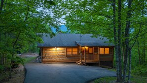 A cabin with a stone facade, a porch, and a driveway leading to the entrance. - True Log Cabin W/ ⛰Stunning Views⛰, Hot Tub, Sauna, Pool Table (Gatlinburg)