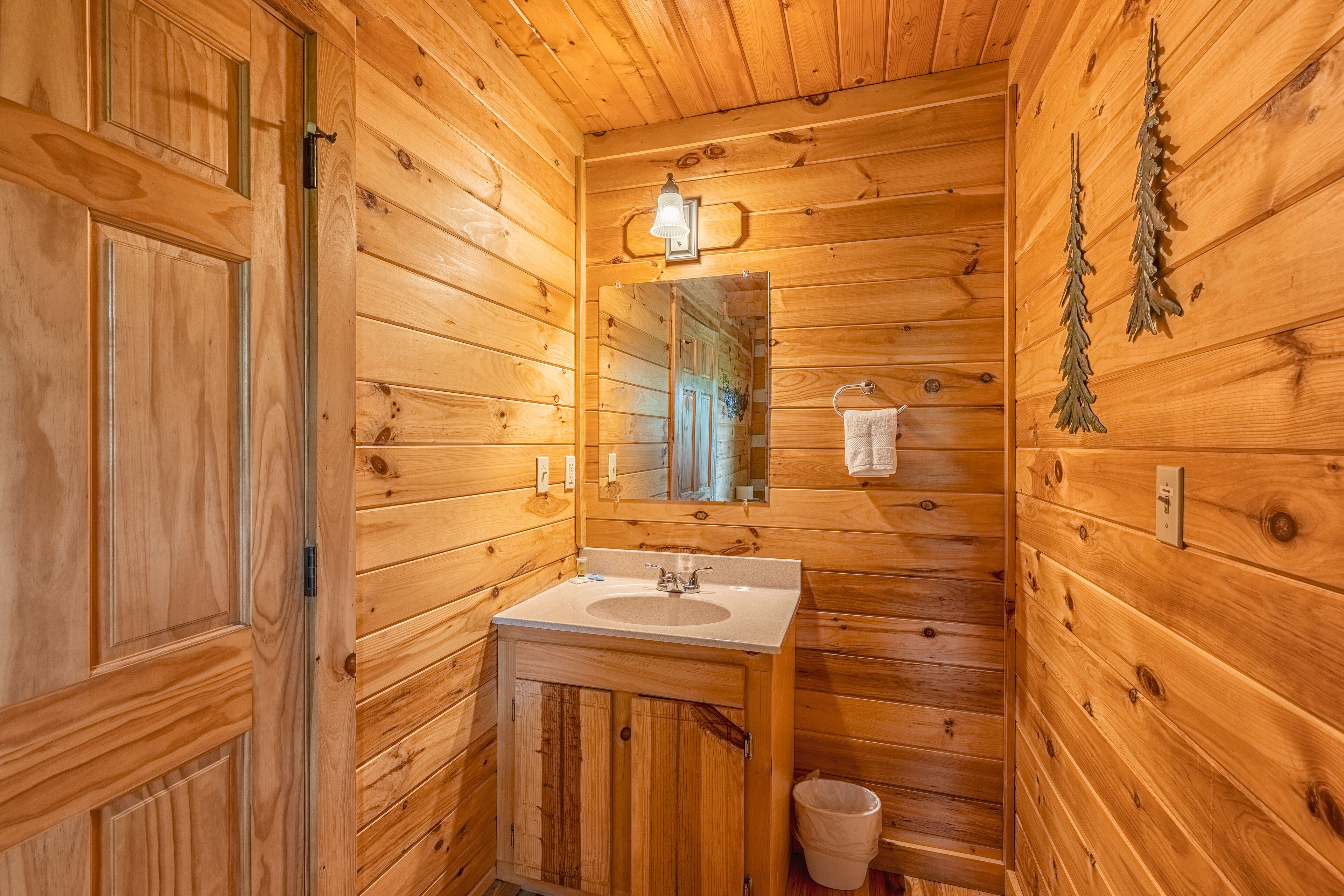 A wooden cabin bathroom with a sink, mirror, and wooden walls.