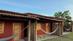 A row of wooden doors with a red wall, a hammock, and a clear sky. - Beautiful Dendê Chalet 5 min from Corumbau Beach (Prado - Corumbau)