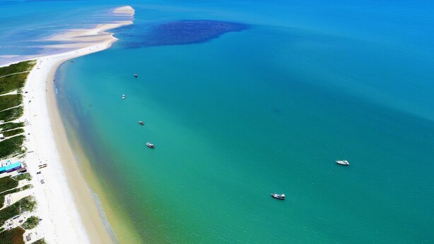 An aerial view of a beach with clear turquoise waters, several boats, and a sandy shore with some structures. - Beautiful Dendê Chalet 5 min from Corumbau Beach (Prado - Corumbau)