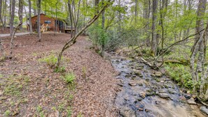 Una cabaña en un bosque con un arroyo.