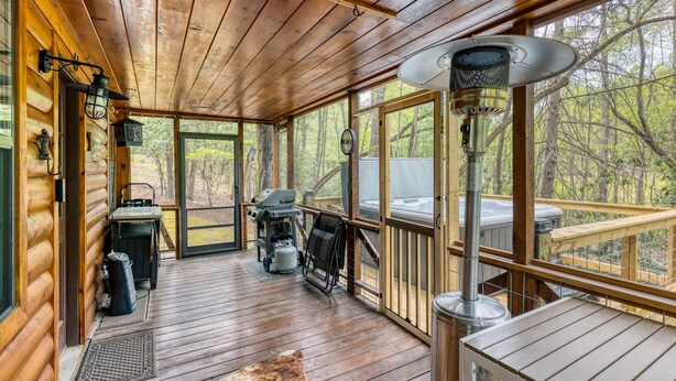 Una terraza de madera con una parrilla, un jacuzzi y un ventilador grande.