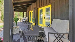 A covered porch with a table and chairs, a potted plant, and a yellow door. - Modern Lakefront Loft Retreat ~ Private Beach & Water Toys (Little Elm)