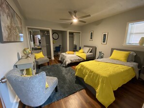 Une chambre avec deux lits, un bureau, une chaise, un globe terrestre et une horloge.