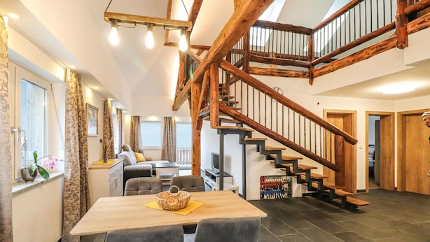 A spacious living area with a wooden staircase, a dining table, and a cozy seating arrangement.