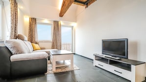 A modern living room with a sofa, coffee table, TV, and a balcony view.