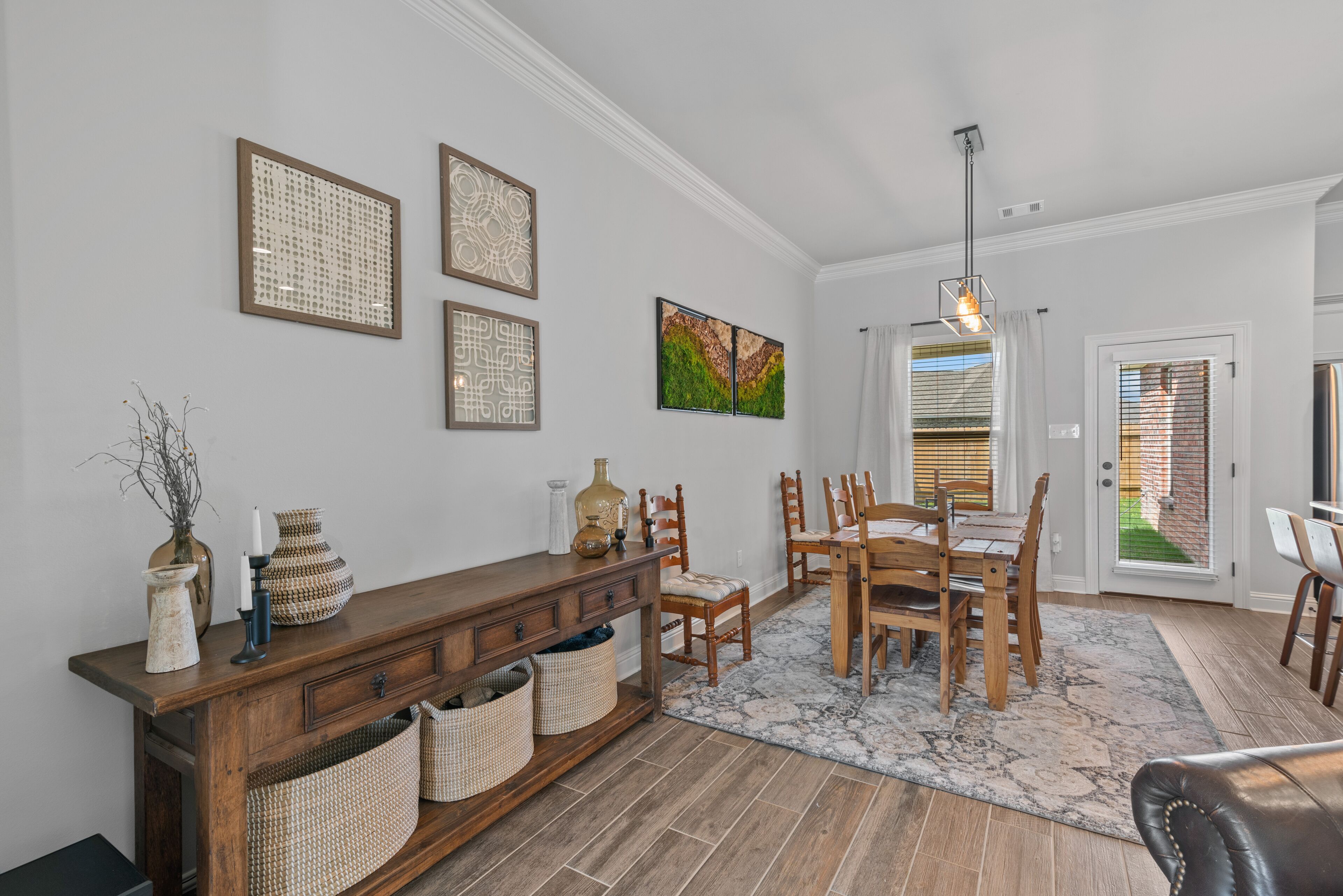 A dining area with a wooden table and chairs, a console table with baskets, and wall art.