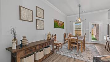 A dining area with a wooden table and chairs, a console table with baskets, and wall art.