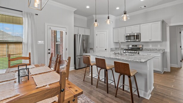 A modern kitchen with white cabinets, stainless steel appliances, and a central island with bar stools. - Brand New Modern Farmhouse (Shreveport)
