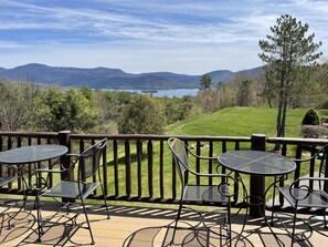 En terrasse med udendørs siddepladser med udsigt over en sø og bjerge.