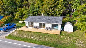 A single-story house with a covered porch, a small shed, and a blue pickup truck parked in front.
