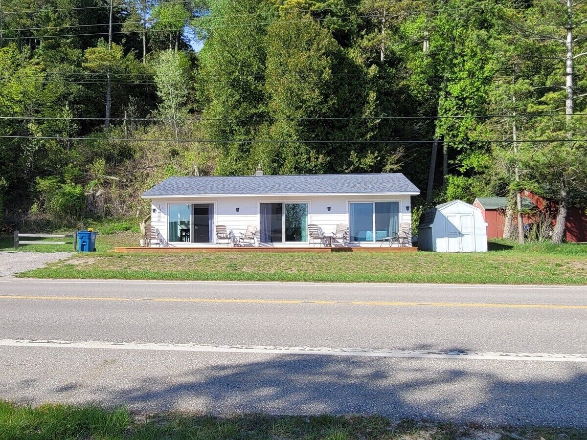 Une maison de plain-pied avec un porche à l’avant, un petit garage attenant et une route dégagée devant.