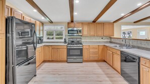 Una cocina con armarios de madera, un refrigerador de acero inoxidable, una estufa y un lavavajillas.