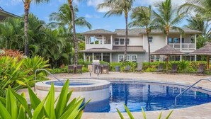 Un área de piscina con un jacuzzi circular, rodeado de exuberante vegetación y palmeras.