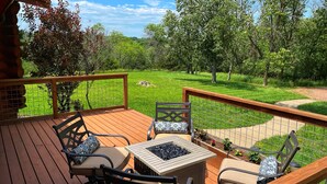 A wooden deck with outdoor furniture, a fire pit, and a view of a grassy yard with trees. - Secluded Lake View Log Cabin on 40 Acres (Yankton)