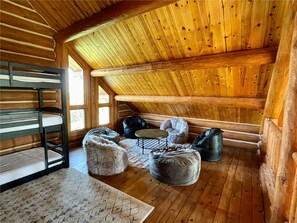 Cozy cabin-style room with a bunk bed, small table, and bean bag chairs.