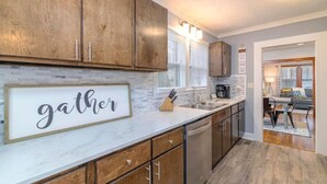 Una cocina moderna con armarios de madera, encimera de mármol y un cartel que dice 'gather'.