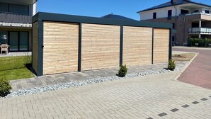 Un edificio moderno con fachada de madera, un sendero pavimentado y un pequeño jardín.