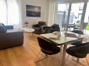 A modern living room with a glass dining table, two sofas, and a coffee table. - 2701 - Strandwiese 16 - Apartment 2701 in the Strandwiese (Dahme)