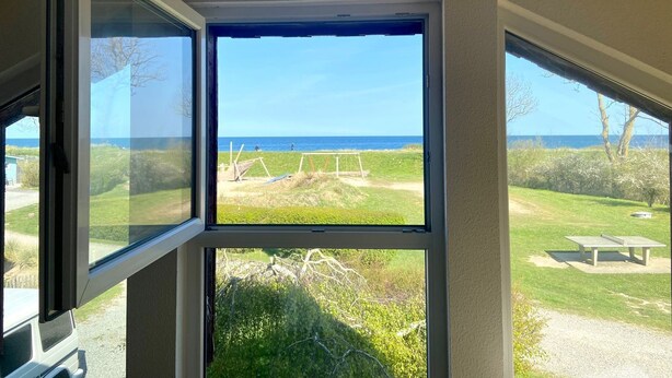 A room with a large window overlooking a grassy area with a bench and a swing set.