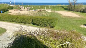 A beach area with a sandy path, grassy areas, and a swing set.
