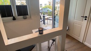 Ein modernes Zimmer mit Balkon, einem kleinen Tisch mit Kerze und Blick ins Freie.