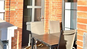 Un patio al aire libre con una mesa, sillas, una puerta y una ventana.