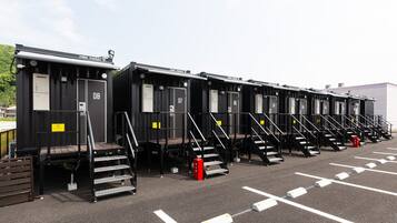 A row of black portable cabins with numbered doors, each with a small staircase leading to the entrance.