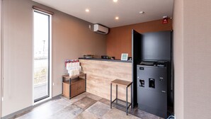 Cocina compacta con refrigerador integrado, un pequeño armario de madera y una puerta corrediza de vidrio que da a un balcón.