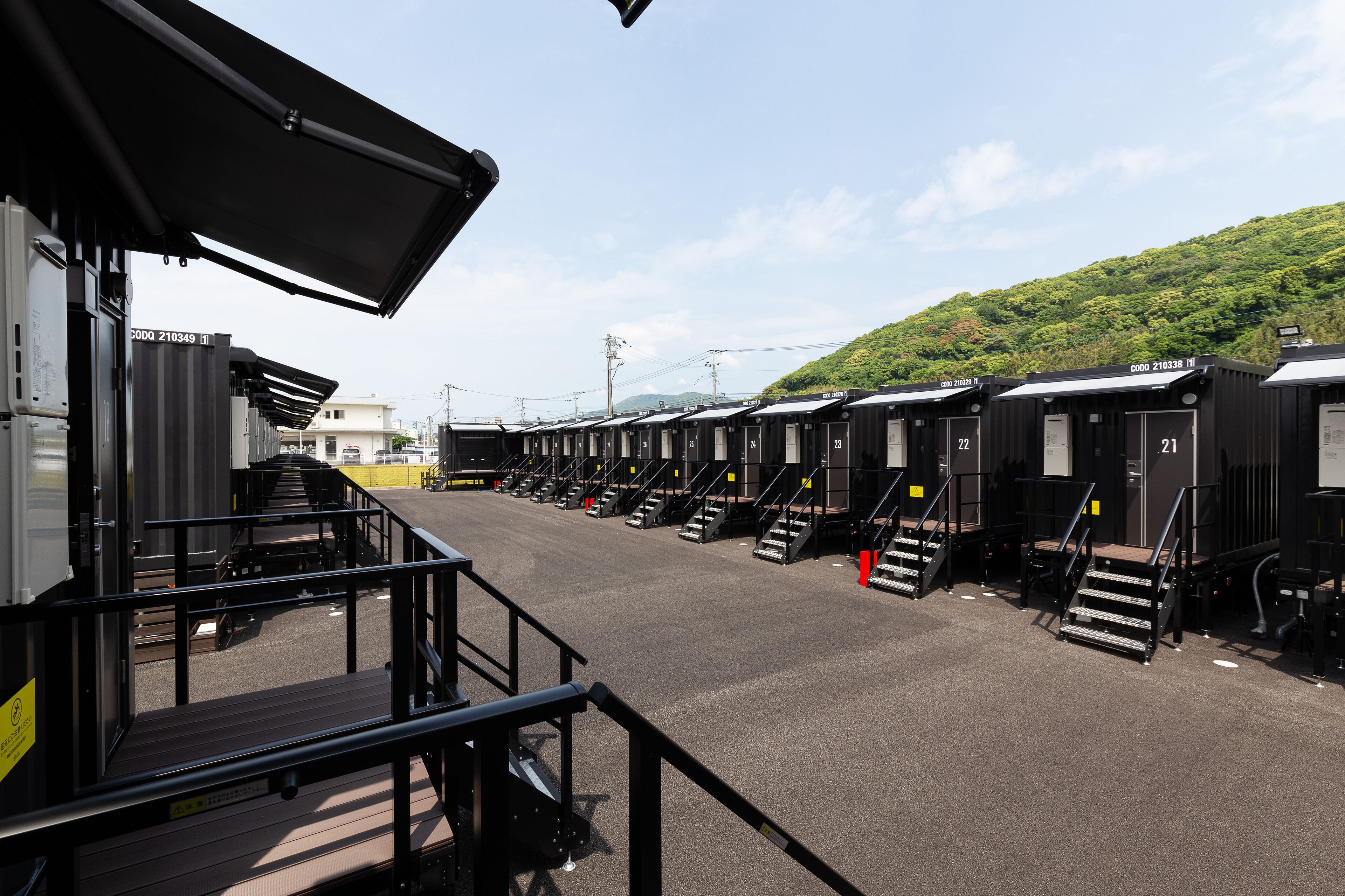 A row of black train carriages with numbered doors, a covered waiting area, and a staircase leading to the carriages.