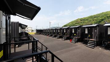 A row of black train carriages with numbered doors, a covered waiting area, and a staircase leading to the carriages.