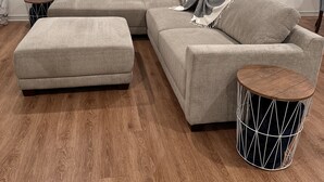 A living room with a sectional sofa, an ottoman, and a round side table.