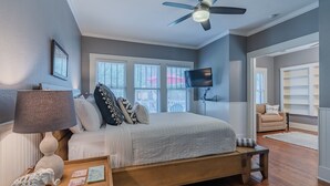 Une chambre à coucher avec un lit, une table de chevet, une lampe et un ventilateur de plafond.