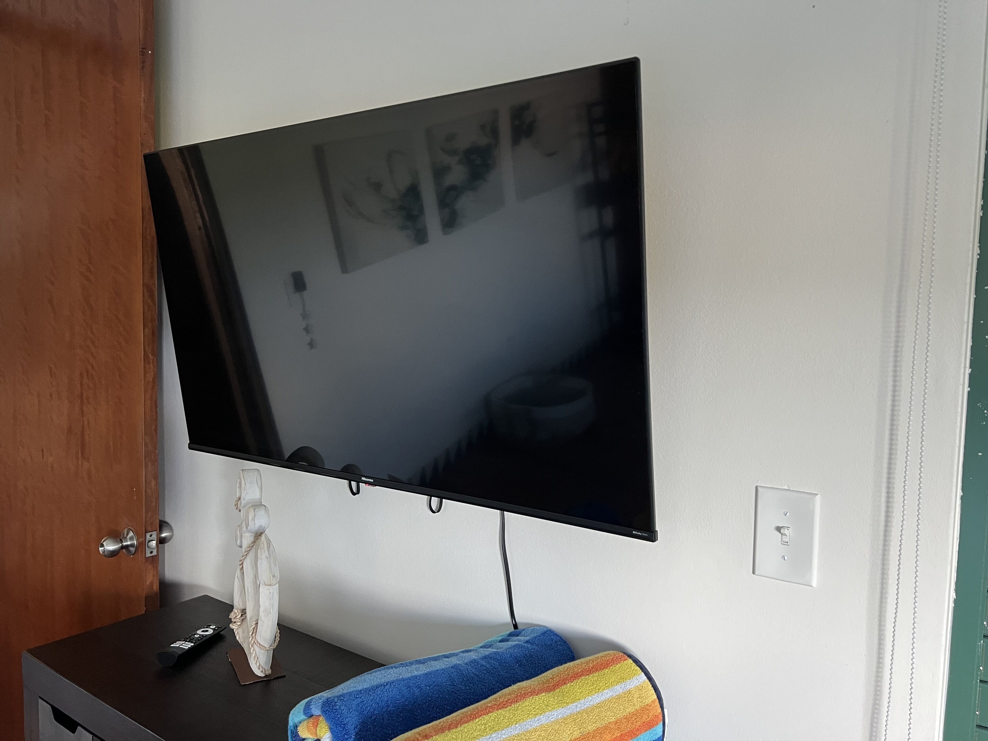 A flat-screen TV mounted on a wall above a dark wooden cabinet.