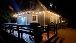 Ein Holzhaus mit Veranda, Lichterkette und einer Flagge.