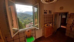 A kitchen with a large window, a wooden cabinet, and a tiled backsplash. - Captivating 1-Bed Apartment in Gerano (Gerano)