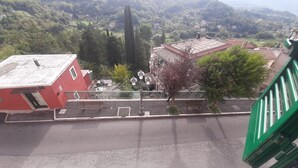 A red building with a sloped roof, a street with benches, and a green railing. - Captivating 1-Bed Apartment in Gerano (Gerano)