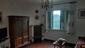 A room with a wooden cabinet, a fireplace, a window with green shutters, and a view of greenery outside. - Captivating 1-Bed Apartment in Gerano (Gerano)